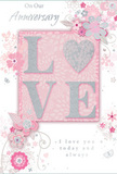 This anniversary card design radiates a gentle, romantic warmth, reminiscent of a pastel bouquet delivered to a townhouse near Queen's Park station. At the centre, the word LOVE appears in bold, raised lettering, each letter coated in soft glitter with fine silver accents that shimmer like dew on early-morning petals. The word rests on a blush pink panel, subtly pearlescent, providing a calm focal point against the card's softly tinted background. Flowing outward from this central motif, clusters of stylised flowers and graceful leaves spread across the surface, their colours held to a dreamy palette of blush pinks, pearly whites, and pale grey lines. The blooms have a hand-drawn quality, as though a florist-artist has sketched them while planning an anniversary arrangement for a couple in nearby Kensal Green or Willesden Green. Curving vines and swirling tendrils link each floral cluster, creating a sense of motion like a gentle breeze through a garden. Slight touches of metallic silver highlight certain petals and flourishes, catching the light without overpowering the softness of the design. Scattered among the flowers are tiny hearts and discreet decorative swirls that add to the theme of enduring romance. In a fluid, elegant script, the printed message expresses anniversary wishes and a promise of love that lasts, perfectly in keeping with the delicate visual style. The entire composition feels light, refined, and intimate, ideal for marking a special anniversary in Queen's Park with both fresh flowers and a meaningful, beautifully designed card.